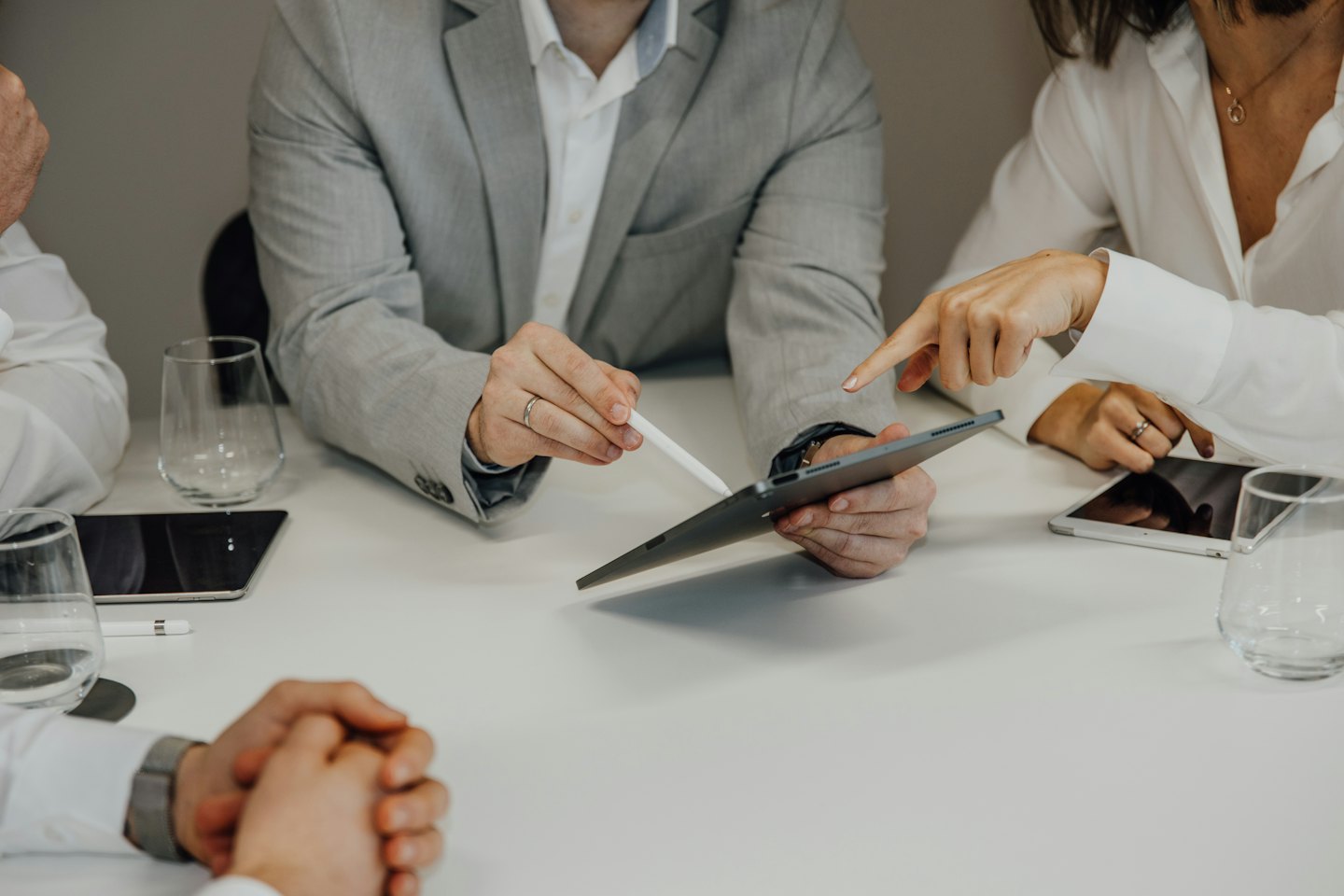 Profesionales de negocios colaborando en una tableta sobre una mesa blanca.