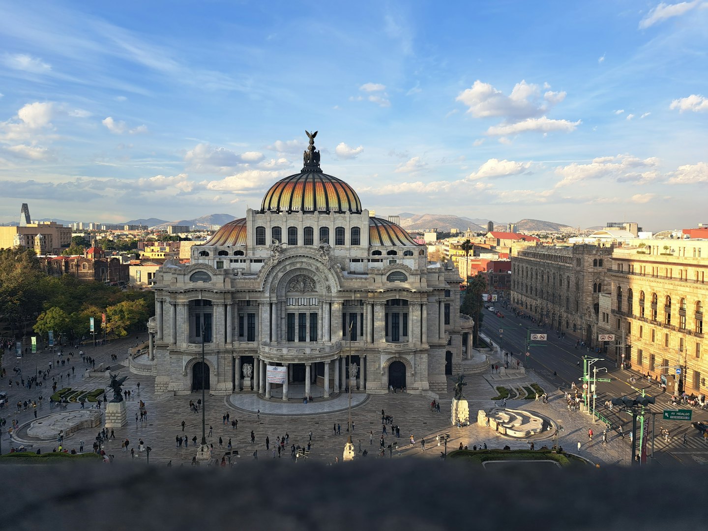 Edificio ornamentado con techo abovedado se alza en una plaza concurrida.