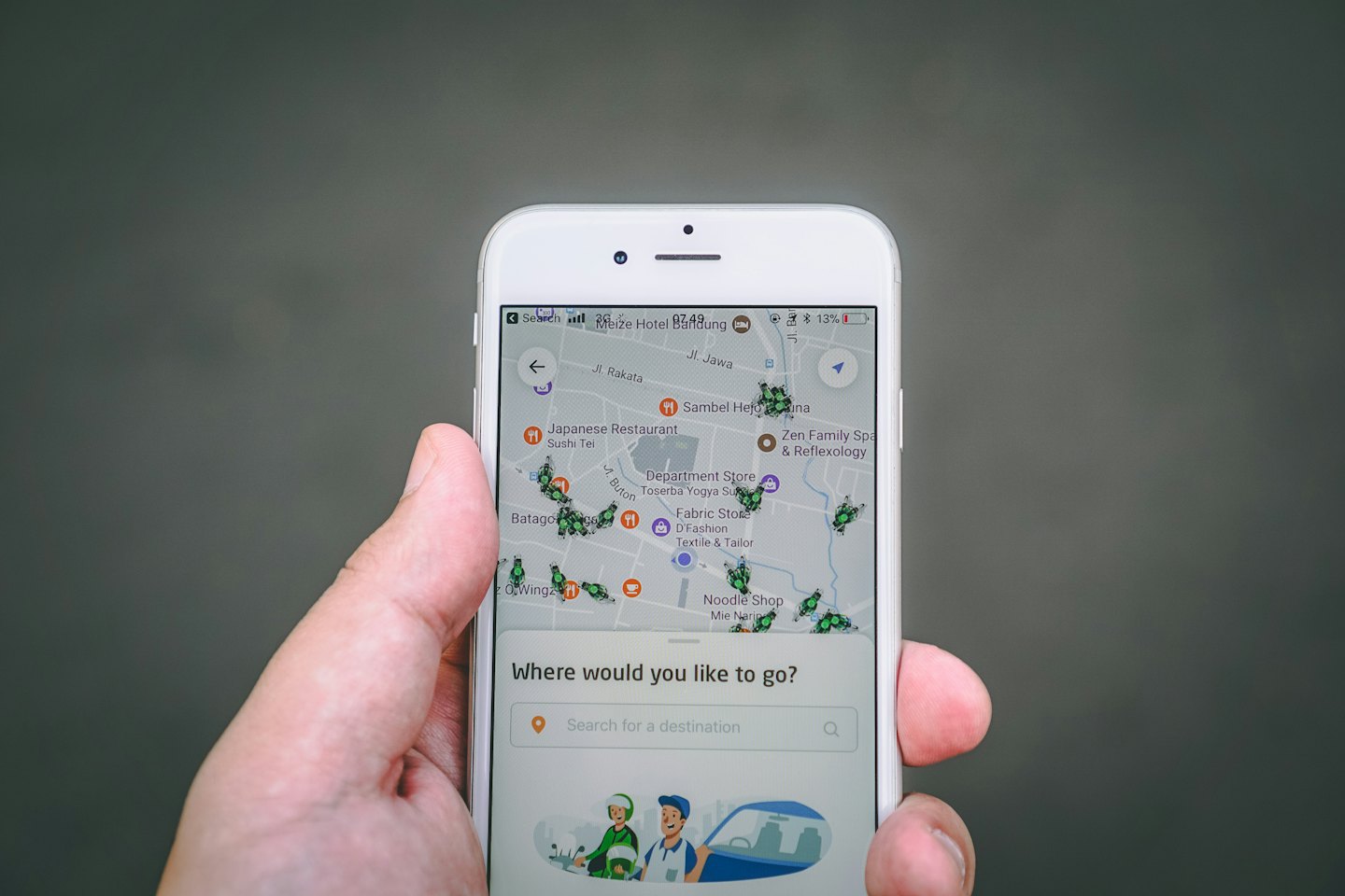 Mano sujetando un smartphone que muestra un mapa con iconos de entrega.