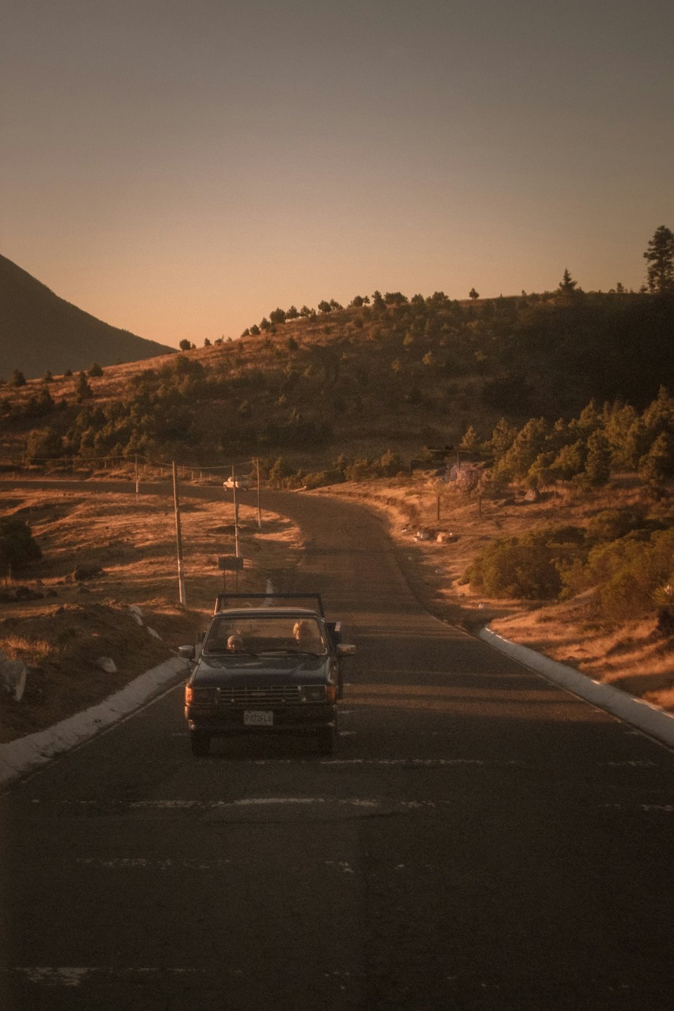 Camioneta azul oscuro en una carretera sinuosa a través de las montañas.