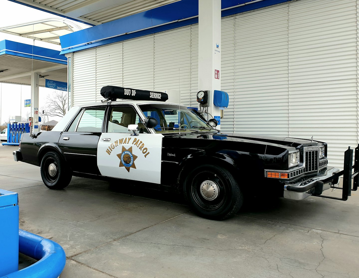 Coche de la policía de carreteras aparcado en una gasolinera exterior.